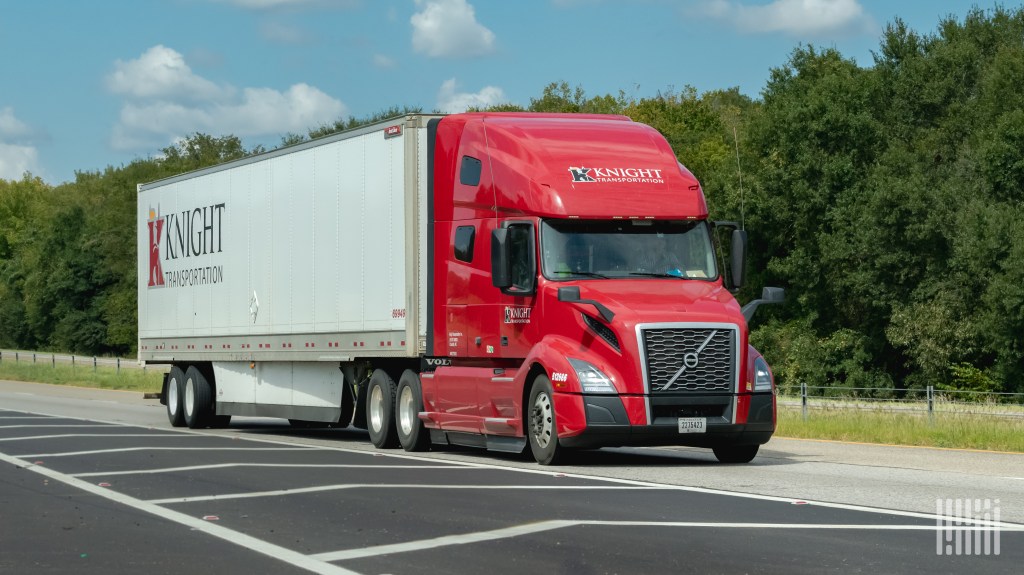 A red Knight sleeper cab pulling a white Knight trailer on a highway