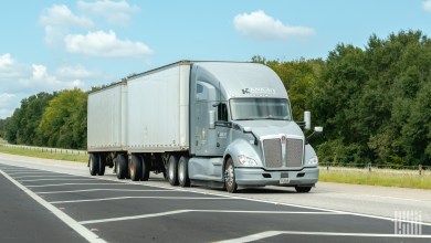 A silver Knight sleeper cab pulling two pup trailers on a highway