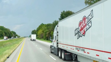 A white Heartland tractor pulling a white Heartland dryvan trailer