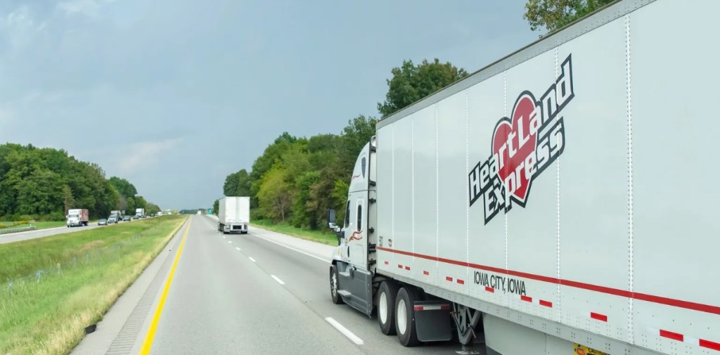 A white Heartland tractor pulling a white Heartland dryvan trailer