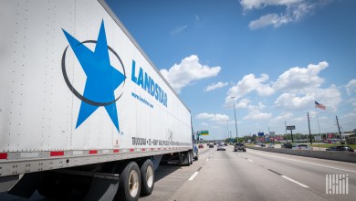 A white Landstar trailer being pulled on a highway