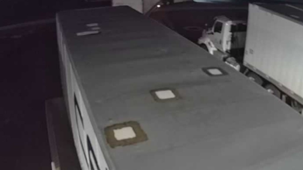 Black-and-white security photo of a truck trailer at night at a warehouse.
