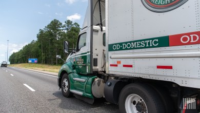 A closeup of an Old Dominion tractor pulling a trailer on a highway