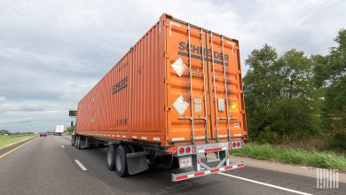 An orange Schneider intermodal container being pulled on a highway
