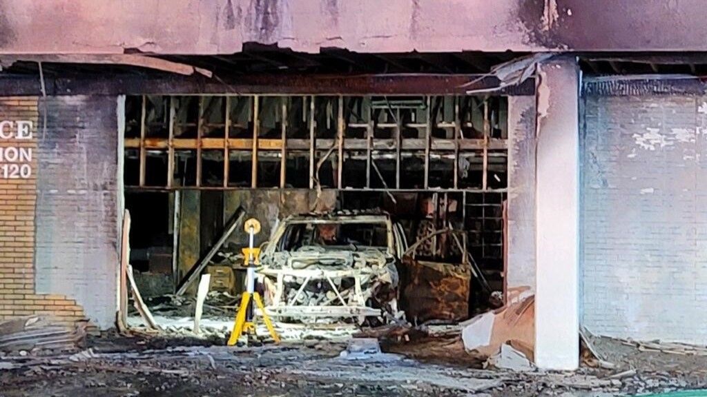 The charred remains of a post office and a vehicle after they were intentionally set on fire.
