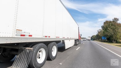 a white trailer being pulled by a red tractor on a highway