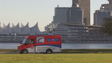 A red-and-white Canada Post van drives along a river in Vancouver.