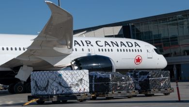 Side view of Air Canada jetliner with a cargo container next to it on tarmac.
