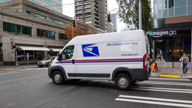 A U.S. Postal Service van passes an Amazon Go store on a Seattle street.