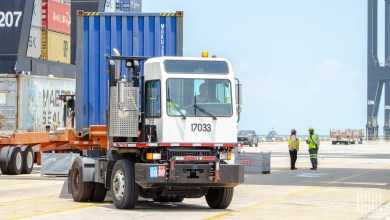 a yard truck moving an ocean container at a port