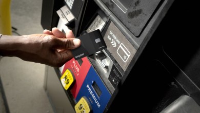 Hand tapping Motive fuel card at gas pump for fleet cost tracking and compliance.