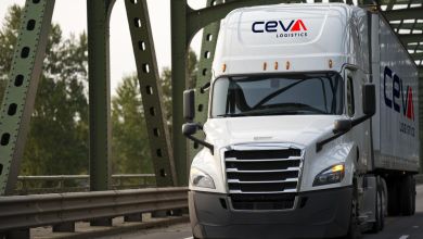 A white Ceva truck moving toward camera on a bridge.