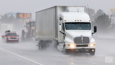 A white tractor pulling a white trailer on a rainy highway