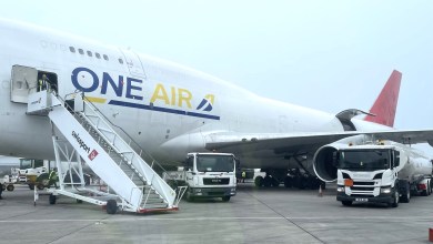A One Air jumbo jet seen with the rear cargo door open and stairs leading to the cockpit door.