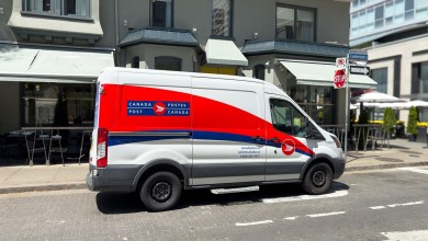 A red-white-and-blue Canada Post delivery is parked on a city street.