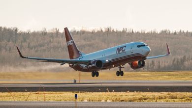A red-tailed NAC freighter aircraft takes off from a rural airfield.