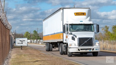 A white Yellow tractor pulling an old USF Holland dryvan trailer near a terminal