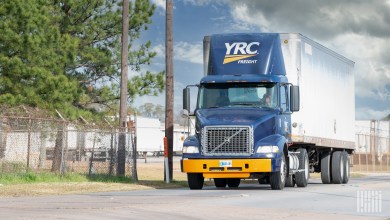 A blue YRC tractor pulling a dryvan trailer outside of a Yellow terminal
