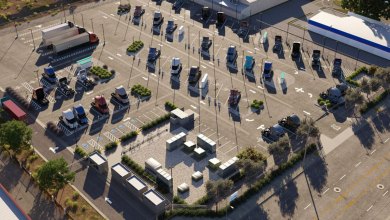 Aerial view of EV Realty's San Bernardino charging hub, featuring 76 DC fast-charging stalls for over 200 Class 8 trucks daily, with parked vehicles and grid infrastructure.