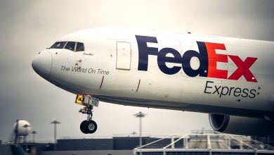 A close-up view of the front of a FedEx plane about to land on a runway.