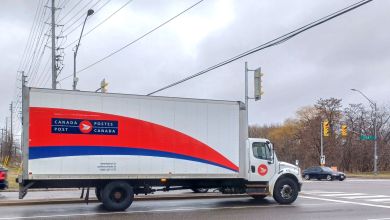 A large Canada Post box truck is seen on a roadway.