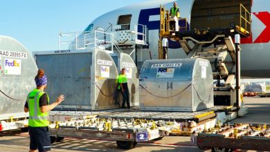 Containers get loaded in the side door of a FedEx cargo jet using a mechanical lift.