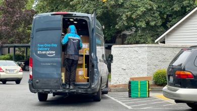 Rear view of an Amazon Prime delivery van with driver looking inside for package in an residential garden apartment complex.
