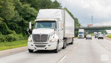 a white tractor pulling a white trailer on a highway