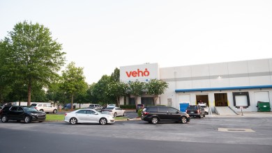 A Veho parcel terminal with cars in line to enter and be loaded with packages for delivery routes.