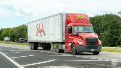 A red Saia truck pulling a trailer on a highway