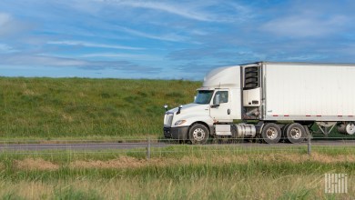 A white tractor pulling a white reefer trailer on a highway