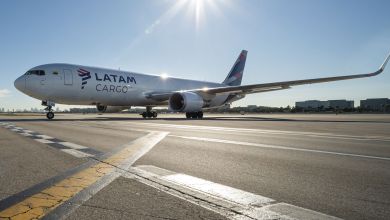 A Latam Cargo plane with blue lettering sits on tarmac with suns rays bouncing off it.