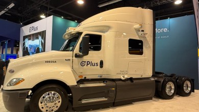 PlusAI autonomous semi-truck, model 1003SA, displayed at a trade show booth with Plus branding, sensors on the cab, and USDOT 3173394 visible.