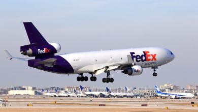 A purple-tailed FedEx freighter with three engines lands at an airport.
