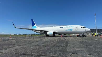 A standard-size jet with dark-and-light blue accents sits on the tarmac on a sunny day.
