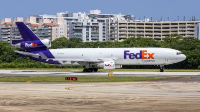 A purple-tailed FedEx plane prepares to take off as seen from side on a sunny day.