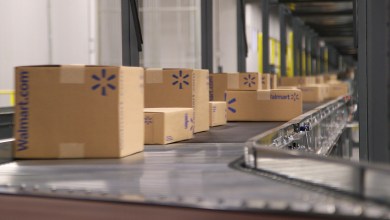 Cardboard Walmart boxes move on a conveyor belt in a warehouse.