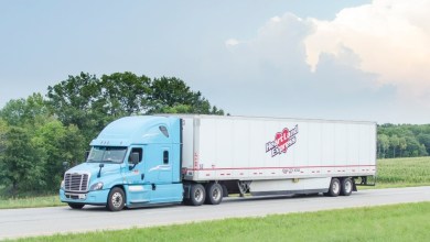a light blue sleeper cab pulling a Heartland Express trailer on a highway