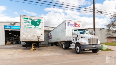 A FedEx Freight tractor-trailer at a warehouse next to a R+L Carriers trailer