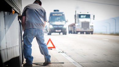 trucker repairing truck at on roadside.