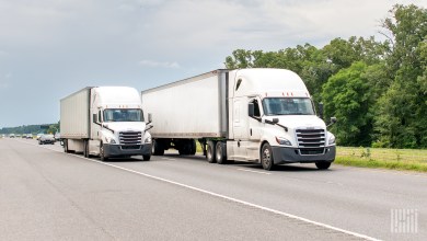 two white tractor-trailers on a highway