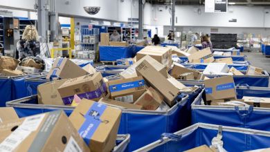 Carts full of mail parcels at a USPS sort center.