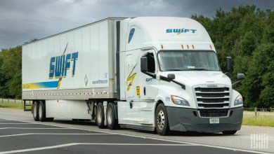 A white Swift sleeper cab pulling a Swift trailer on a highway
