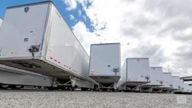 Row of white dry van semi-trailers parked in a gravel lot, showcasing fleet trailers now visible via Phillips Connect-McLeod Software integration with real-time smart trailer insights, tire health, brake monitoring, location tracking and AI cargo visibility.