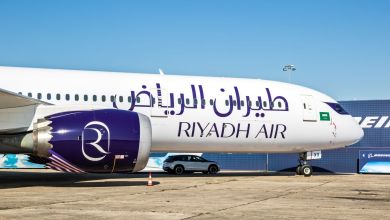 Front half of a Riyadh Air jet, side view at airport on a sunny day.