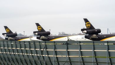 Brown-tailed UPS MD-11 freighter jets parked next to low airport barrier.