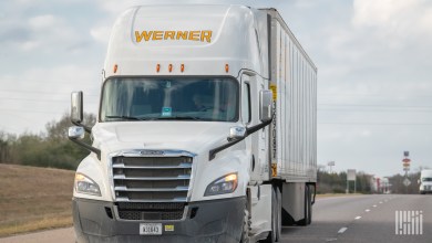 a white Werner tractor pulling a trailer on a highway