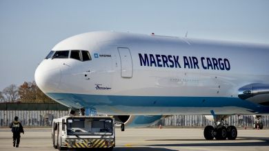 A Maersk Air Cargo freighter with light-blue underbelly as seen close up from the front side.