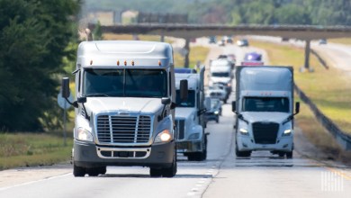 Front view of several tractors pulling trailers on a highway