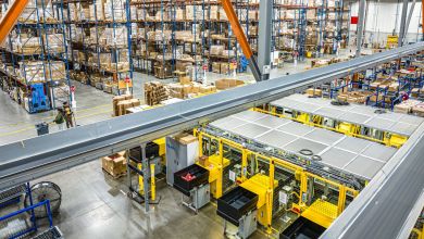 Busy warehouse floor with shelving and parcel chutes.